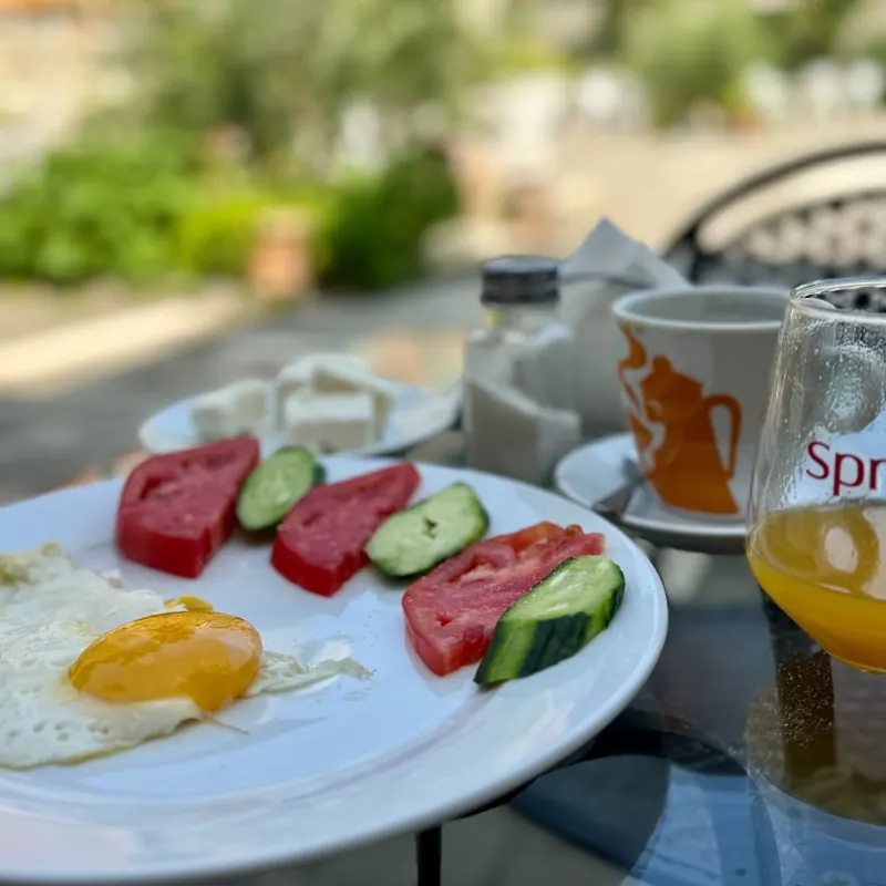 Breakfast outside: fried eggs, tomatoes and cucumber, with coffee and juice on the courtyard table