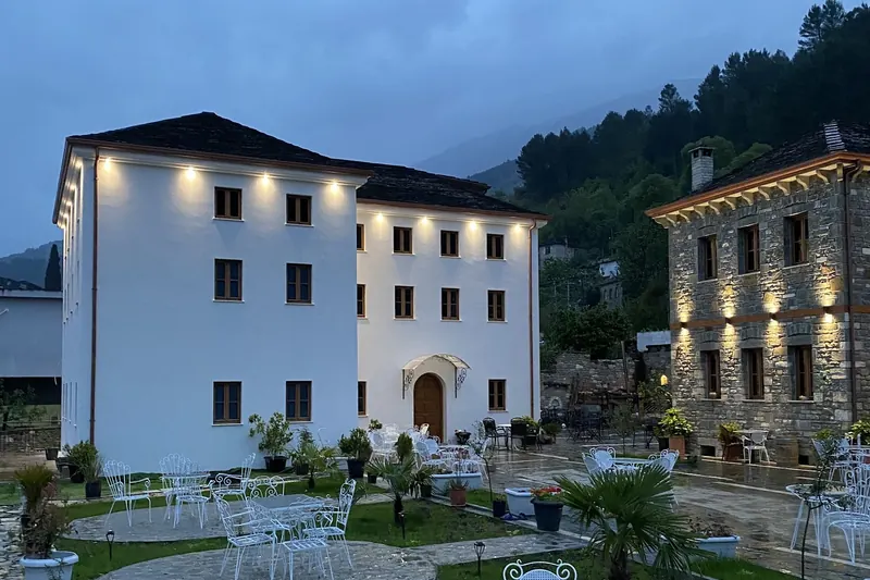 The courtyard in the evening, white iron tables in front of the lit white and stone wings