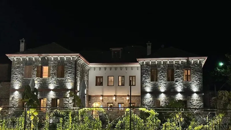 The stone house at night, its facade washed with warm light above the garden